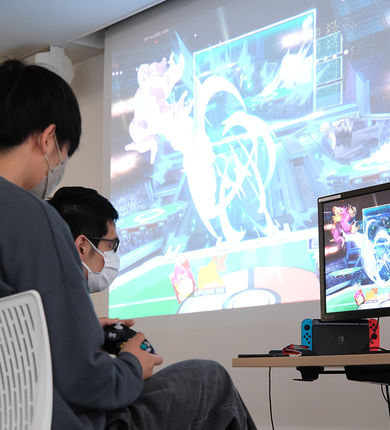 Two students are playing a video game.