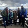 A group photo of people smiling and posing on a wooden deck.