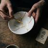 A person mends a broken bowl using gold