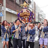 Men and women wearing happi coats and carrying a portable shrine at a Japanese festival