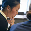 A female student looking down thoughtfully with her hand on her chin during a class discussion.