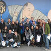 A large group of diverse international Law students posing together for a photo in front of a traditional Japanese sumo mural.