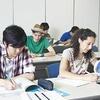 A view of a classroom where students are sitting at their desks, discussing and presenting their analysis using books.