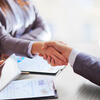 Two business professionals shaking hands across a meeting table