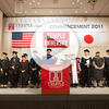 Image of a group of people standing in front of a stage and a banner reading "Temple University.