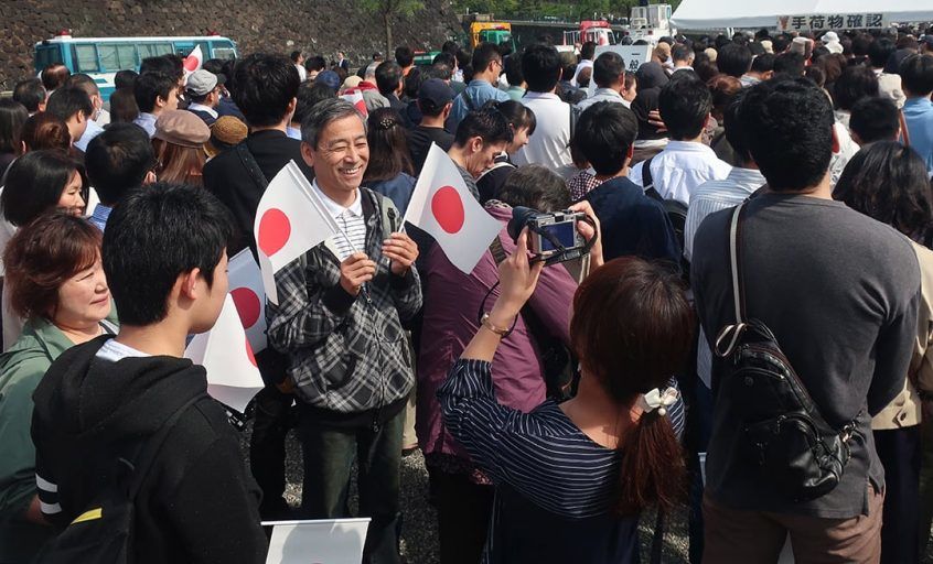 待ち時間に日本国旗と共に記念撮影する人