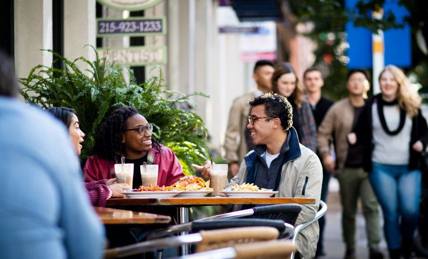 Scenery of the city, people enjoying a meal at cafe.