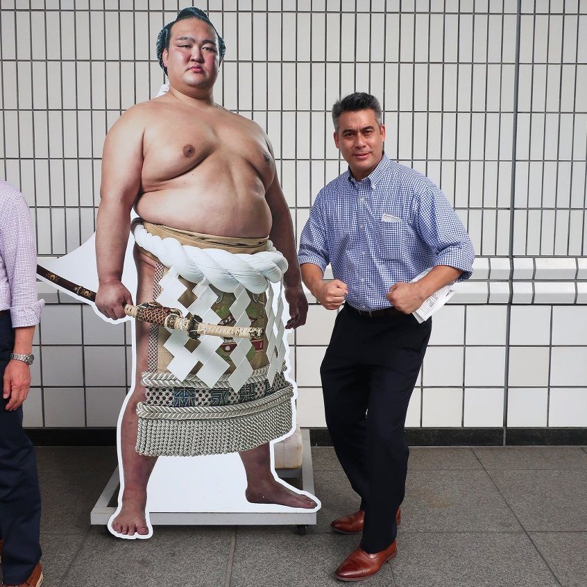 相撲取りの 等身大パネルの横で写真を撮るジョージ