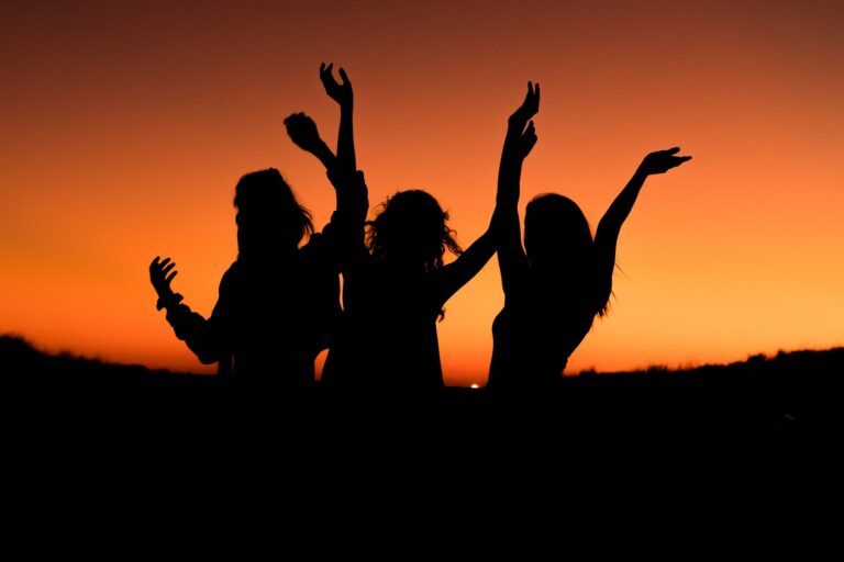 People dancing in front of a sunset