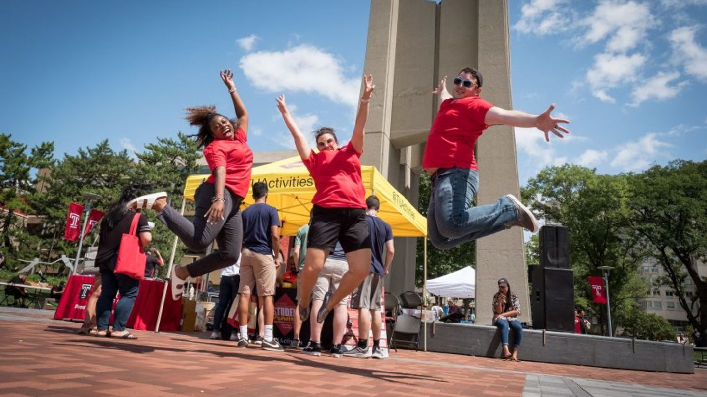 Students striking poses in front of the bell tower in Temple University main campus.